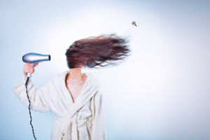 a woman blowing her hair with a hairdryer